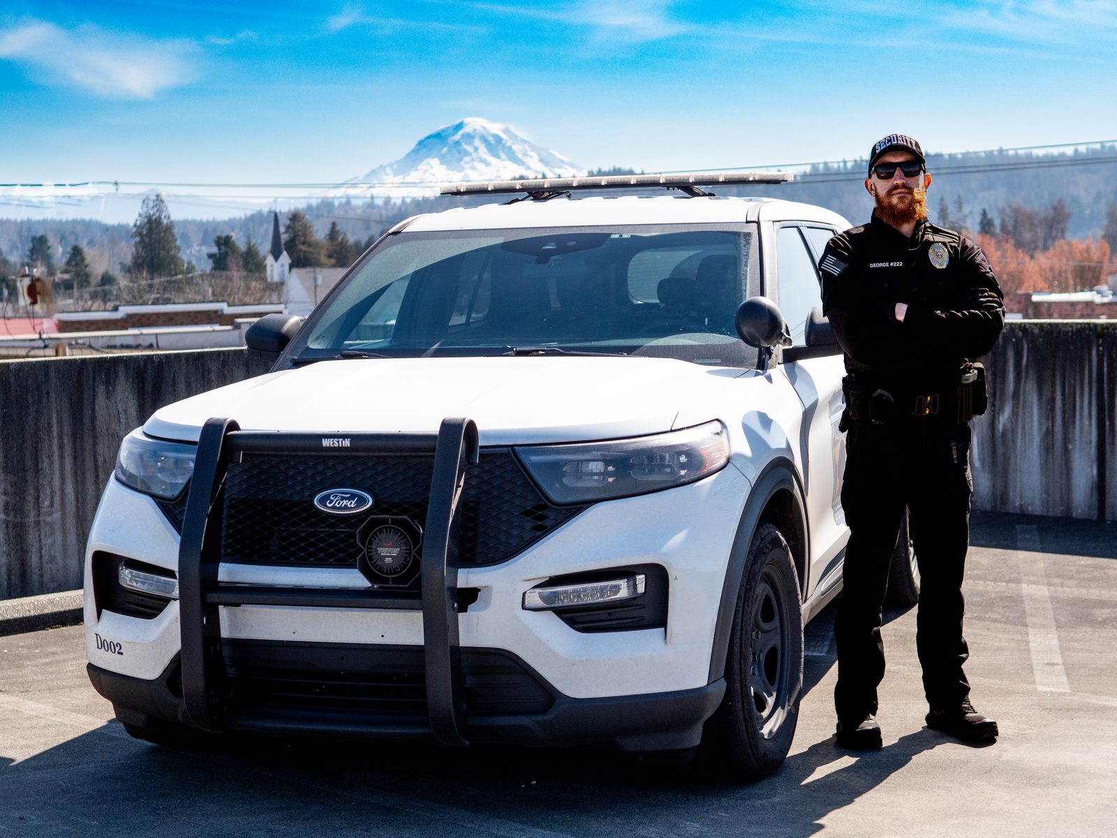 Diligence Security Officer with a marked patrol vehicle in view of Mt. Rainier, providing disciplined patrols throughout Pierce County