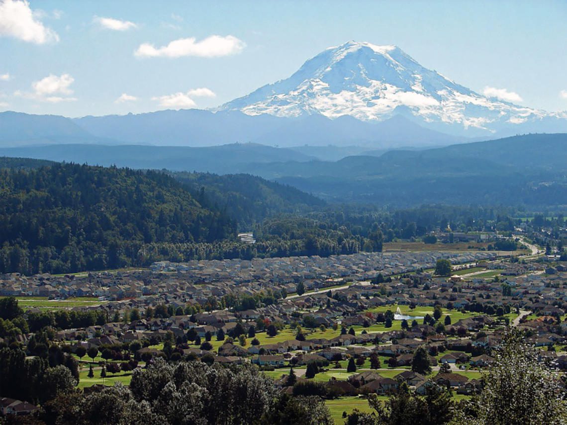 An aerial view of a Pierce County residential neighborhood with Mount Rainier beyond, representing the communities patrolled by Diligence Security.