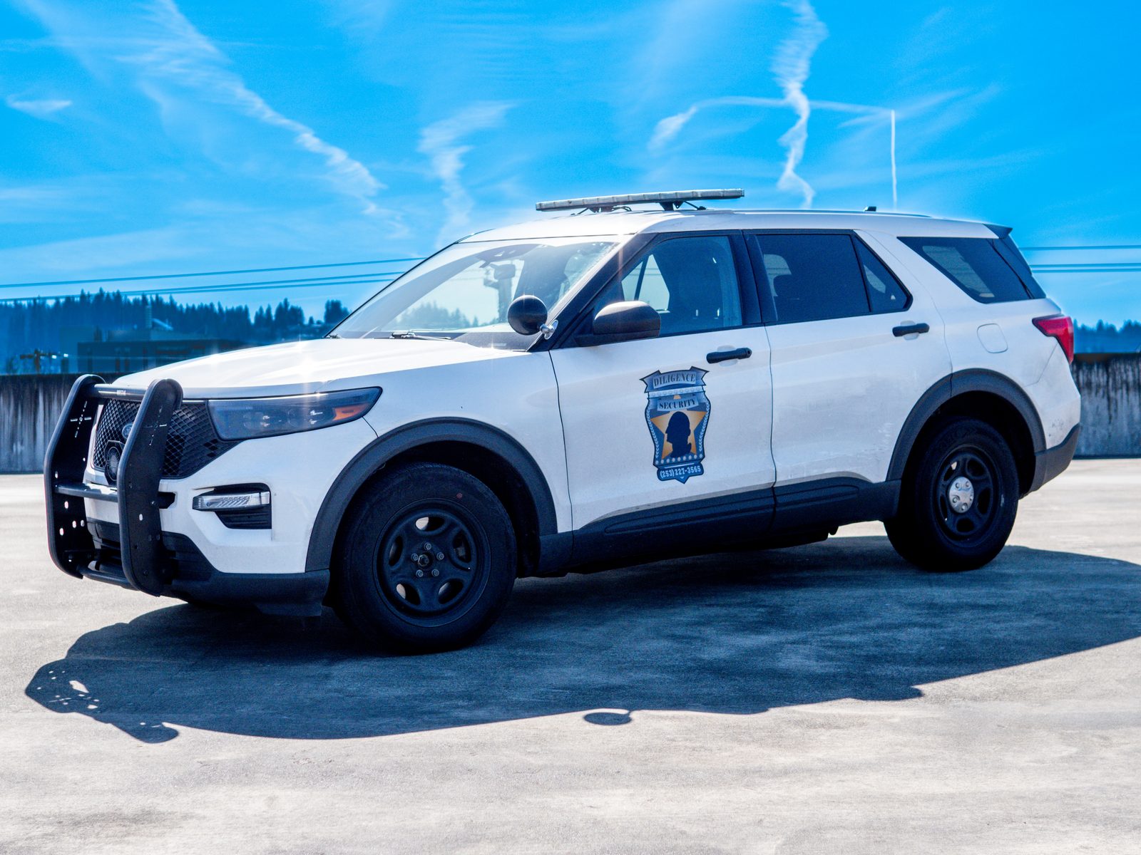 A side-profile view of a Diligence Security white Ford Explorer patrol vehicle with high-visibility door decals.
