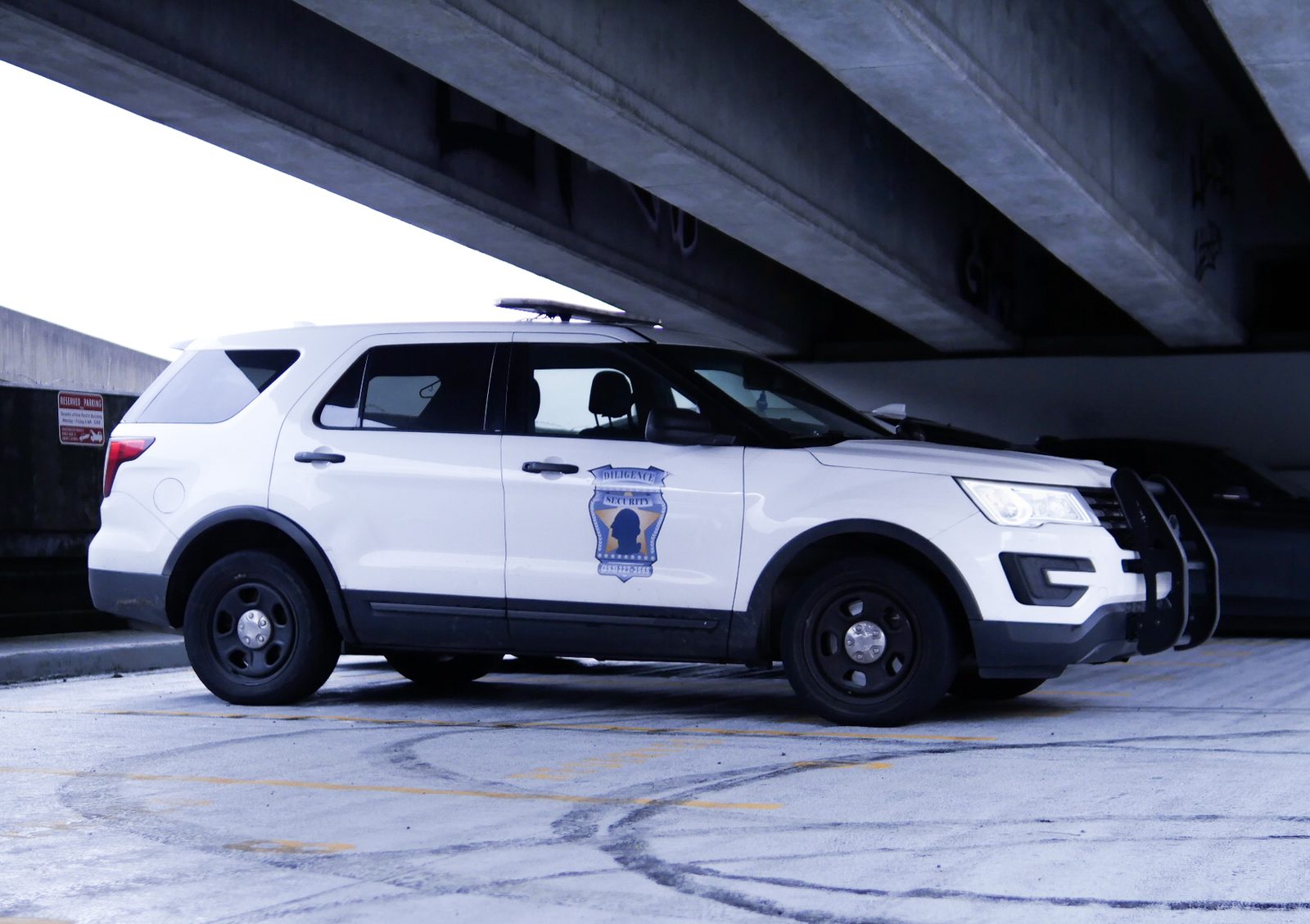 A marked Diligence Security patrol vehicle conducting surveillance under a Tacoma overpass at night.