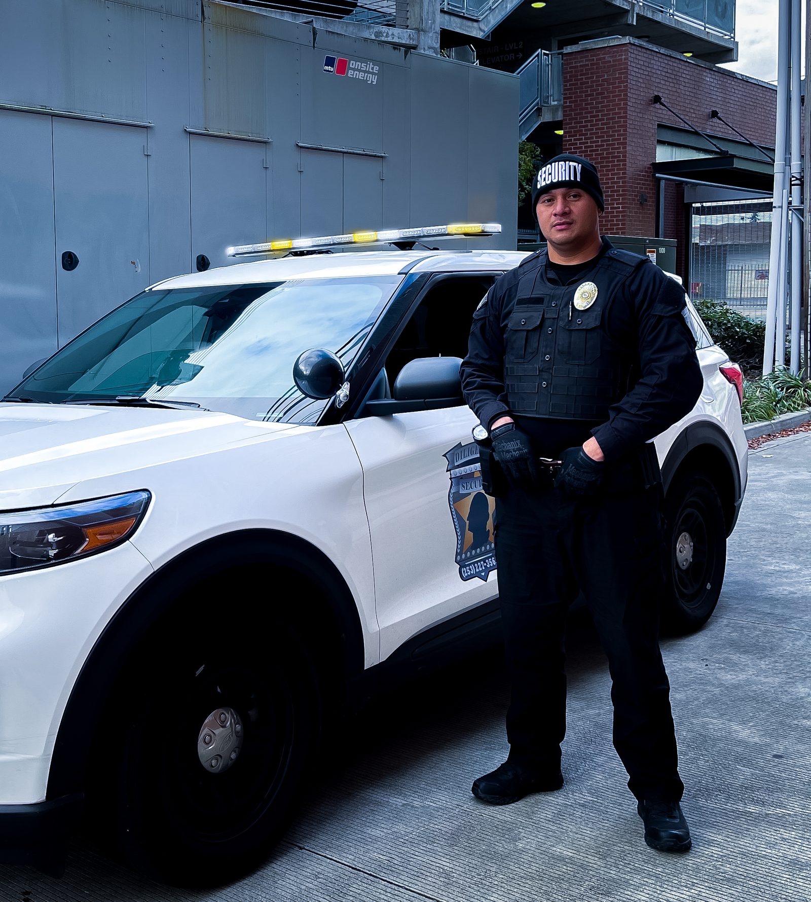 Diligence Security Officer standing guard beside a marked patrol vehicle representing OIP 2 field-ready training